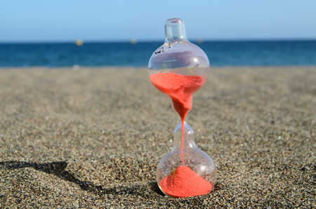 One Hourglass on the Sand Beach Near the Ocean Time Conceptの写真素材
