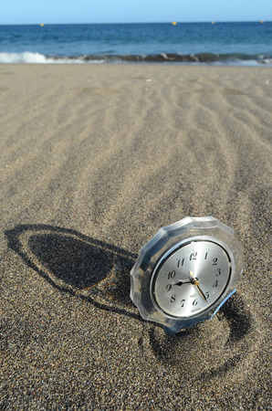 Classic Analog Clock In The Sand On The Beach Near The Oceanの写真素材