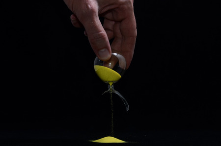 Deadline Concept Broken Hourglass with Yellow Sand on Black Backgroundの写真素材
