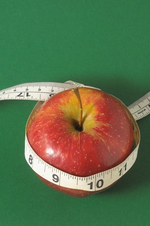 Measuring Tape Wrapped Around a Red Apple as a Symbol of Dietの写真素材
