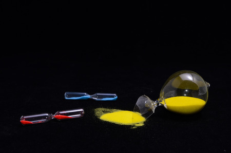 Deadline Concept Broken Hourglass with Yellow Sand on Black Backgroundの写真素材