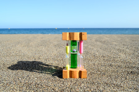 One Hourglass on the Sand Beach Near the Ocean Time Conceptの写真素材