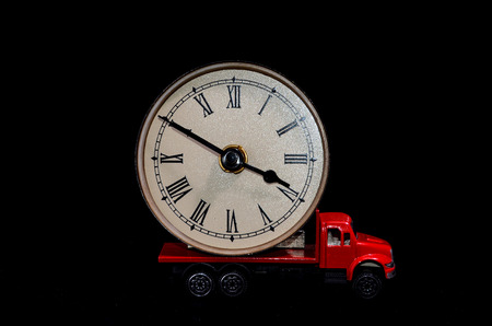 Time Transportation Concept Clock Watch on a Red Toy Truck over Black の写真素材