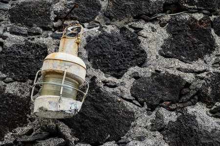 Old Vintage White Kerosene Lantern Light on a Stone Wal