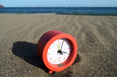 Classic Analog Clock In The Sand On The Beach Near The Oceanの写真素材