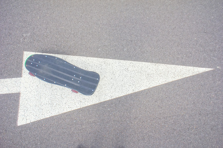 Vintage Style Longboard Black Skateboard on an Empty Asphalt Desert Roadの写真素材