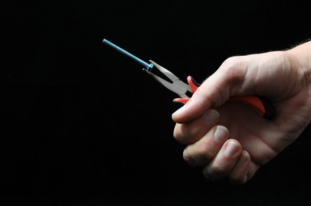 Pliers and a Hand on a Black Backgroundの写真素材