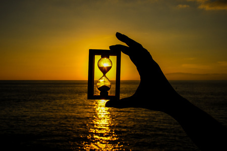 Time Concept Hourglass and Sun Setting on the Atlantic Oceanの写真素材
