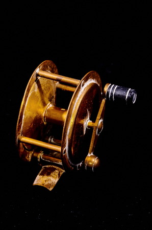 One Vintage Old Metal Fishing Reel on a Black Backgroundの写真素材