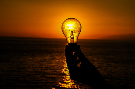 Energy Concept Light Bulb and Sun Setting on the Atlantic Oceanの写真素材