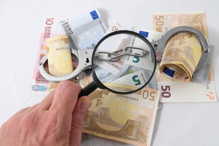 Financial Concept Loupe, Handcuffs and Money on a White Backgroundの写真素材