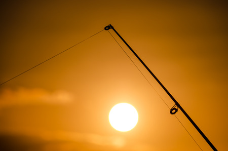 Fisherman Fishing Rod Silhouette at Orange Sunsetの写真素材