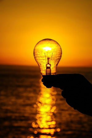 Light Bulb and Sun Setting on the Oceanの写真素材