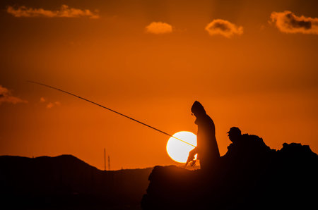 Fisherman Fishing Rod Silhouette at Orange Sunsetの写真素材