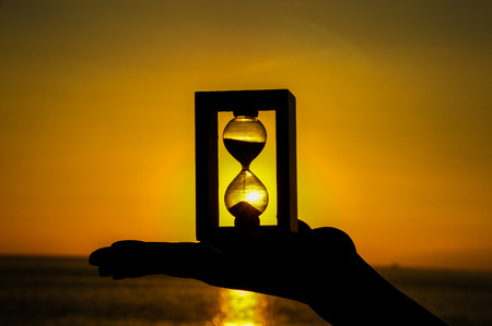 Time Concept Hourglass and Sun Setting on the Atlantic Oceanの写真素材