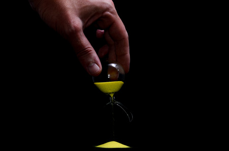 Deadline Concept Broken Hourglass with Yellow Sand on Black Backgroundの写真素材