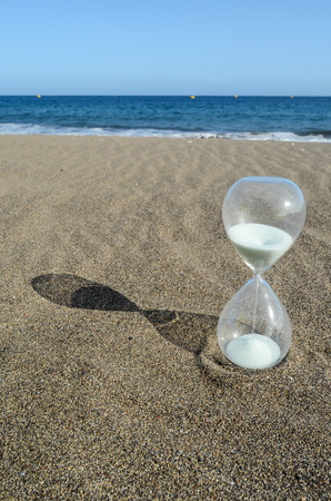 One Hourglass on the Sand Beach Near the Ocean Time Conceptの写真素材