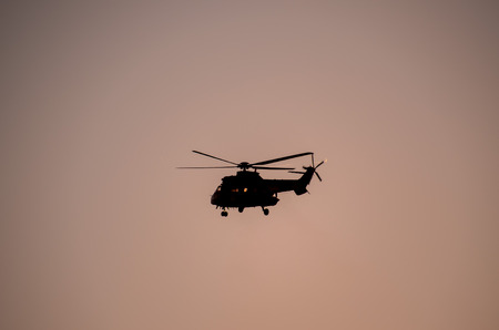 Military Helicopter Silhouette Flying over a Dark Skyの写真素材