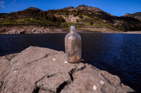 Old Dirty Vintage Gass Bottle near the Waterの写真素材