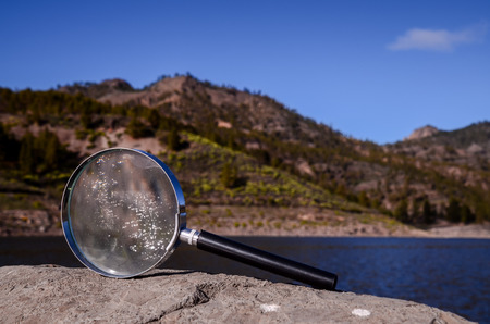 Investigation Concept Magnify Glass Loupe on the Volcanic Rock near a lakeの写真素材