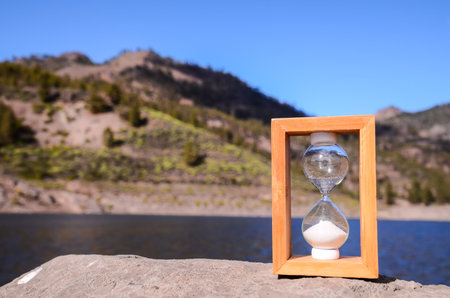 Time Concept White Sand Hourglass on the Volcanic Rocks