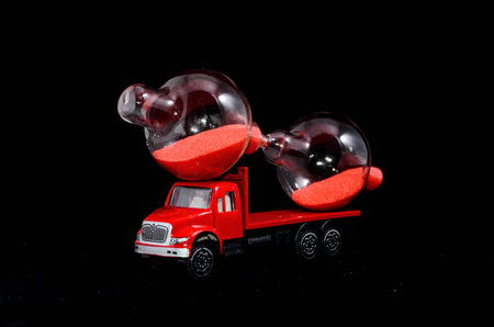 Time Transportation Concept Hourglass Watch on a Red Toy Truck over Black Background