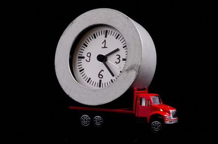 Time Transportation Concept Clock Watch on a Red Toy Truck over Black Backgroundの写真素材