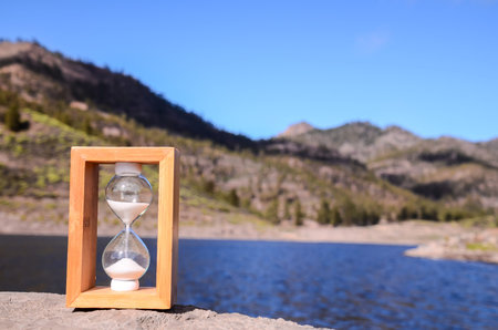 Time Concept White Sand Hourglass on the Volcanic Rocks