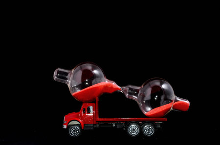 Time Transportation Concept Hourglass Watch on a Red Toy Truck over Black Background