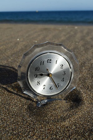 Classic Analog Clock In The Sand On The Beach Near The Ocean