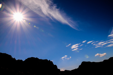 Sun Star on a Blue Sky over a Mountain Silhouette in Gran Canaria Spainの写真素材