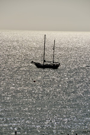 Backlight Picture of a Silhouette Boat in the Oceanの写真素材