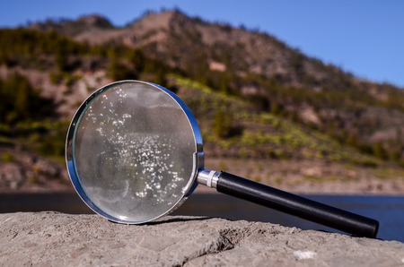 Investigation Concept Magnify Glass Loupe on the Volcanic Rock near a lakeの写真素材