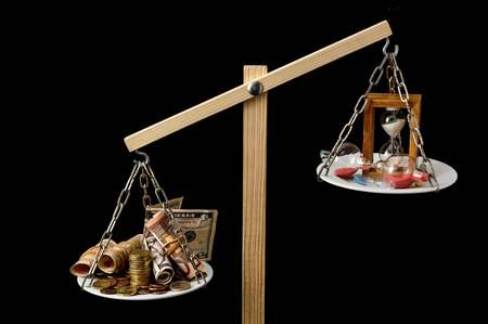 Time is Money Concept Clock and Currency on a Two Pan Balanceの写真素材