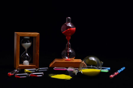 Deadline Concept Broken Hourglass with Yellow Sand on Black Background