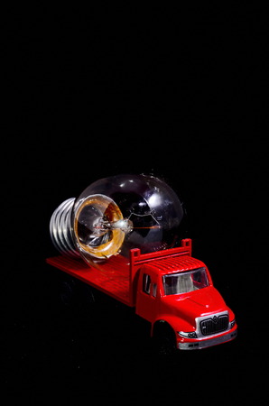Electric Power Concept Red Truck and Light Bulb on a Black Backgroundの写真素材