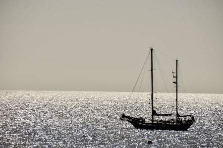 Backlight Picture of a Silhouette Boat in the Oceanの写真素材