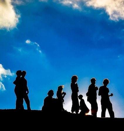 silhouetted people on a mountain on a blue cloudy skyの写真素材