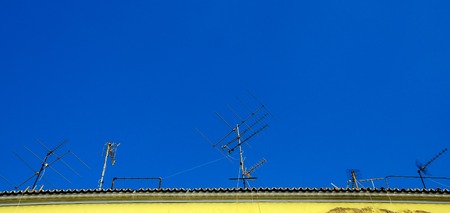 old television antenna on the roof over a blue skyの写真素材