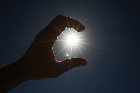 One Hand Catching the Sun Stars on a Blue Backgroundの写真素材