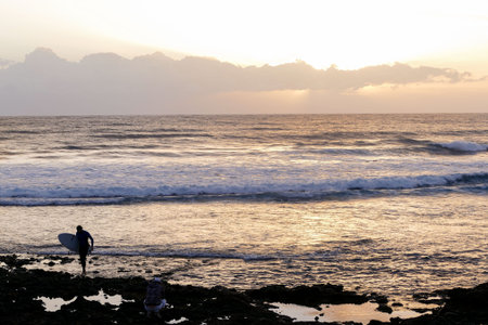 Single surfer at sunset on a calm ocean