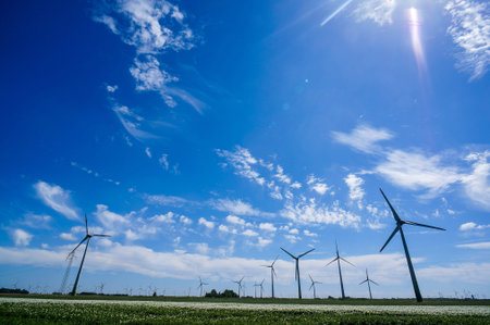 Wind turbines in field with blue sky and clouds.