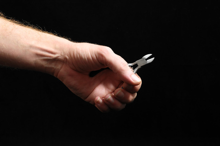Cutter Pliers and a Hand on a Black Backgroundの写真素材