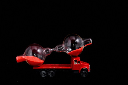 Time Transportation Concept Hourglass Watch on a Red Toy Truck over Black Backgroundの写真素材
