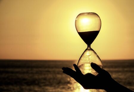 Time Concept Hourglass and Sun Setting on the Atlantic Oceanの写真素材