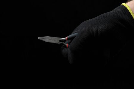 Pliers and a Hand on a Black Backgroundの写真素材