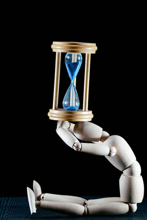 wooden dummy and hourglass sandglass vintage clock, time concept, puppet made of wood, art...