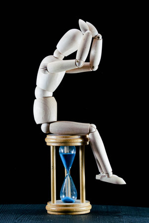 wooden dummy and hourglass sandglass vintage clock, time concept, puppet made of wood, art...