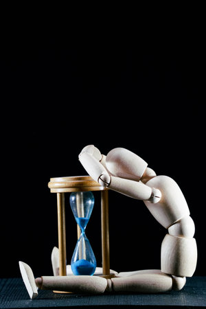 wooden dummy and hourglass sandglass vintage clock, time concept, puppet made of wood, art...