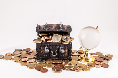 A treasure chest full of coins and a crystal ball. The chest is open and the coins are scattered around it. The scene gives off a sense of mystery and adventureの写真素材